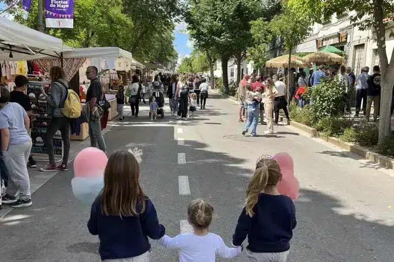 Victoria, con sus hermanas, en las Fiestas de Rivas Vaciamadrid, en la que están agarradas de las manos, Victoria en medio de sus hermanas. Están dando un paseo .